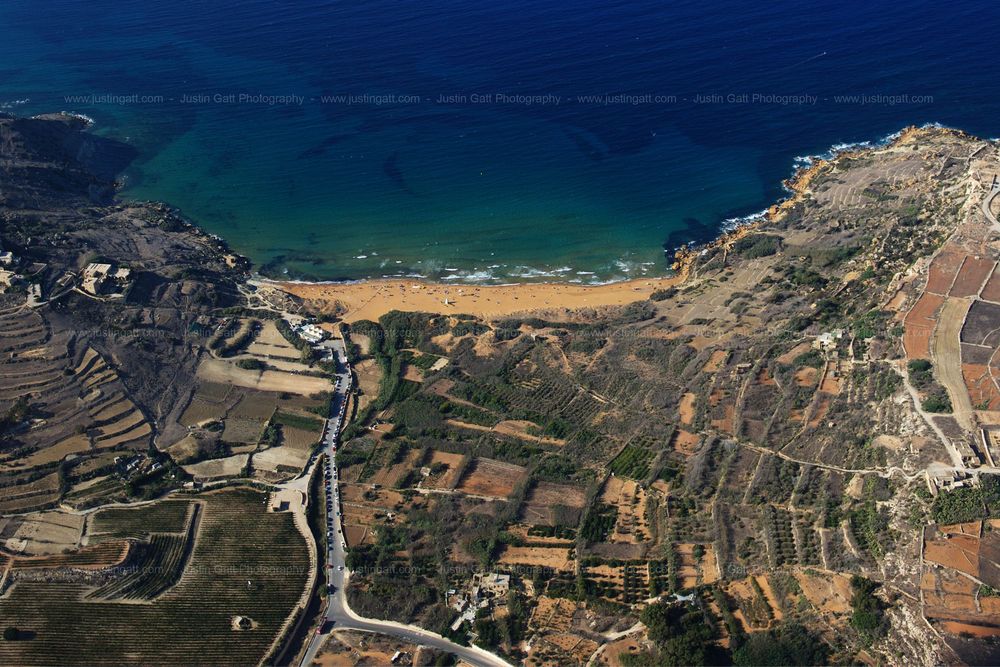 Aerial view of a golden beach nestled between rocky cliffs and turquoise Mediterranean waters.