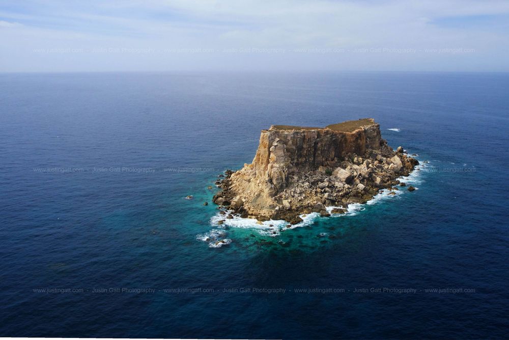 Panoramic view of a rocky island formation surrounded by deep blue Mediterranean waters.