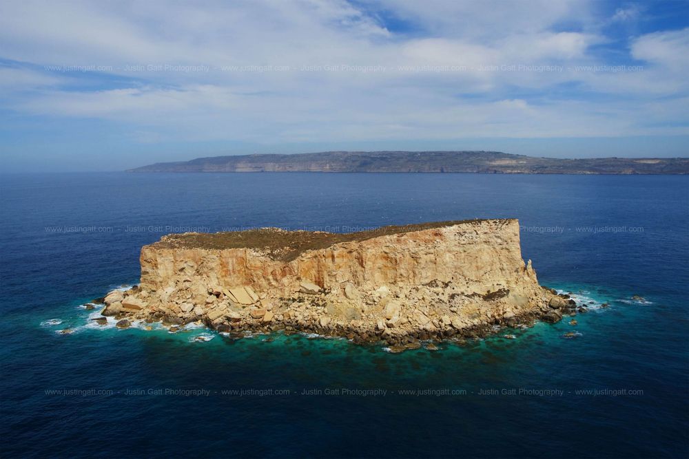 Aerial view of rugged coastal cliffs and rocky outcrops jutting into turquoise Mediterranean waters.