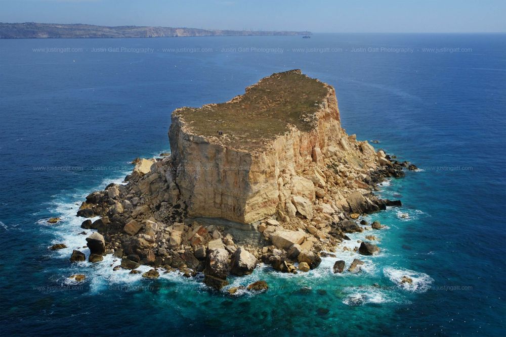 Dramatic limestone cliffs rising from crystal clear Mediterranean waters under bright blue skies.