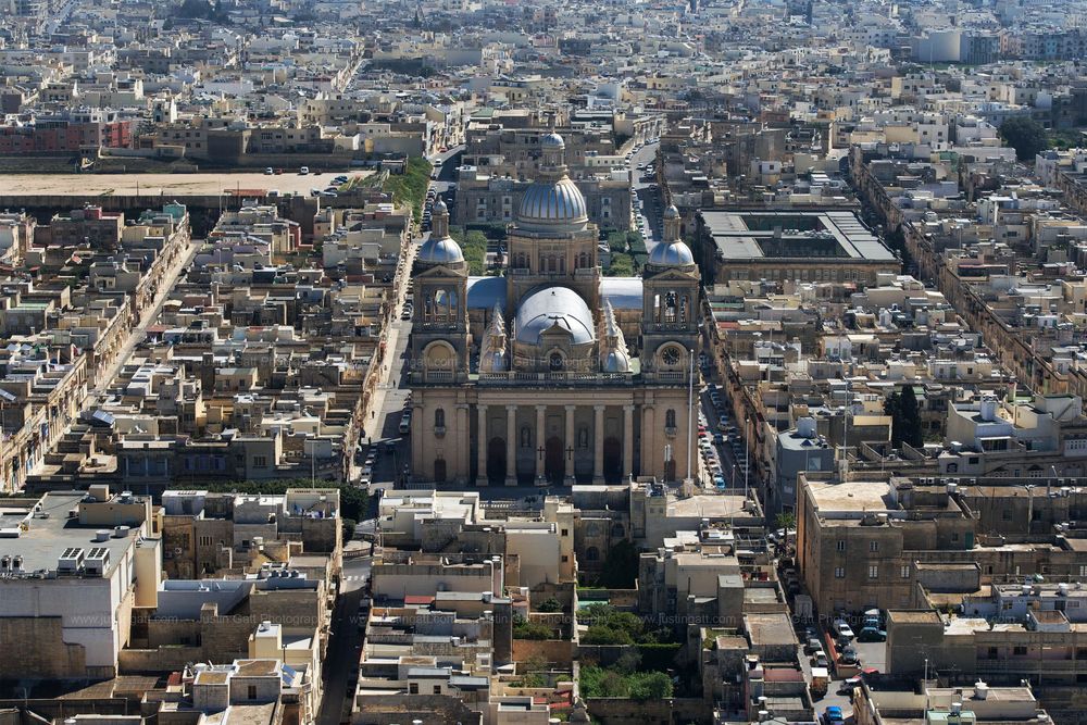 Bird's eye view of a historic Mediterranean cityscape with prominent church domes and buildings.