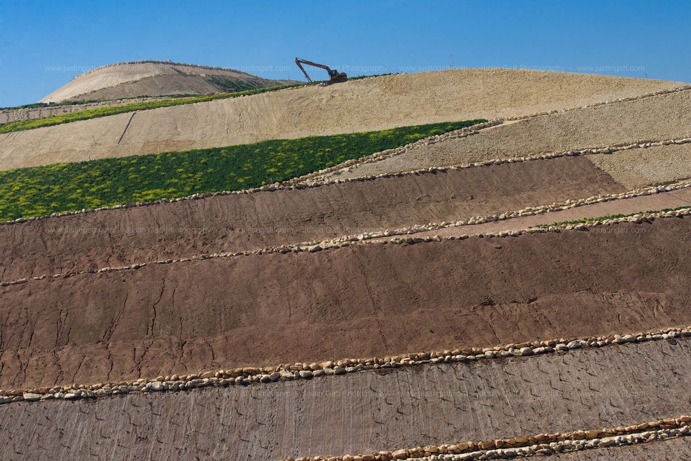 Rolling agricultural fields with terraced stone walls stretching across a rural landscape.