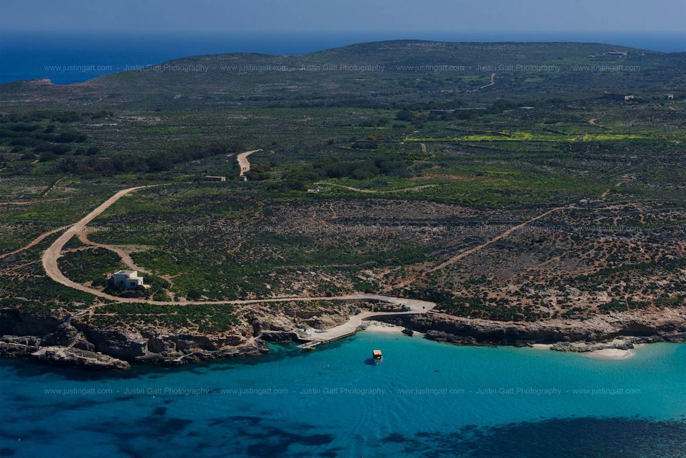 Panoramic coastal landscape showing a bay with clear blue waters and undeveloped shoreline.