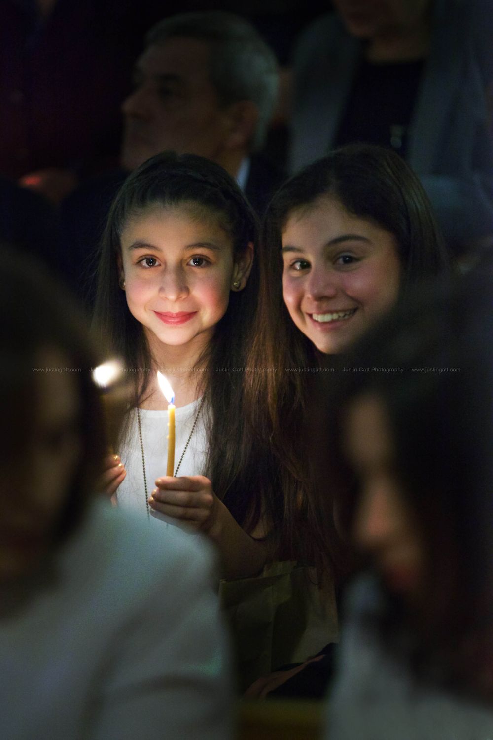 Two people illuminated by candlelight in a dark setting create a dramatic atmospheric portrait.