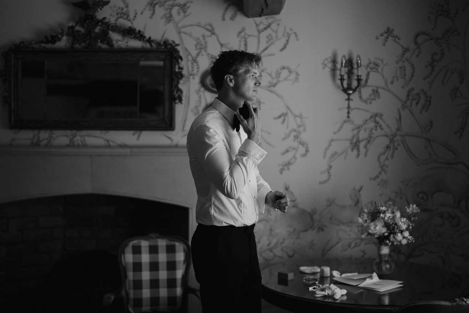 Groom spraying cologne on his neck at dewsall court in herefordshire