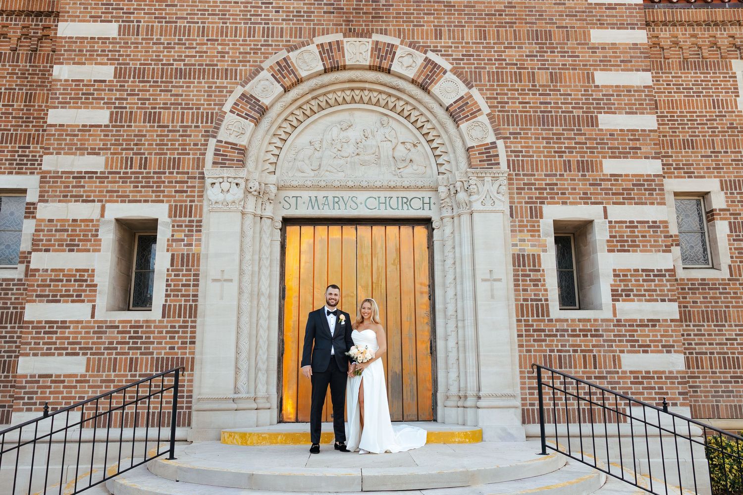 A bride and groom pose together at the entrance of St. Marys Church on their wedding day.