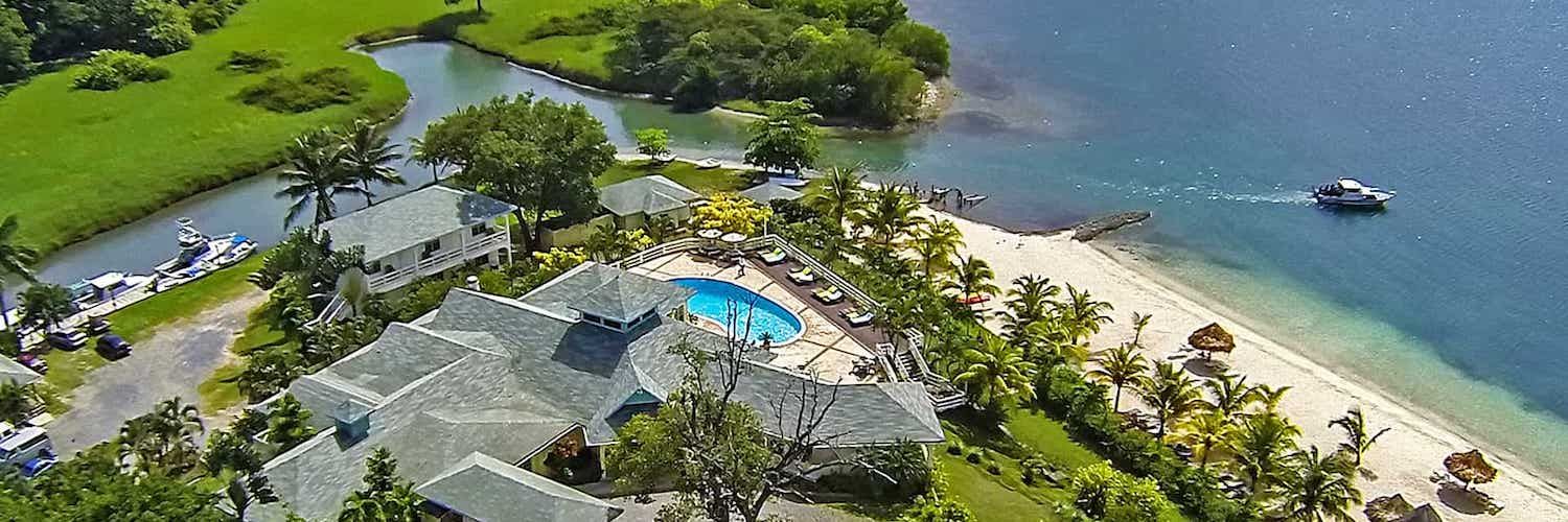 Aerial view of a tropical resort with swimming pool, beach access, and lush green landscaping.