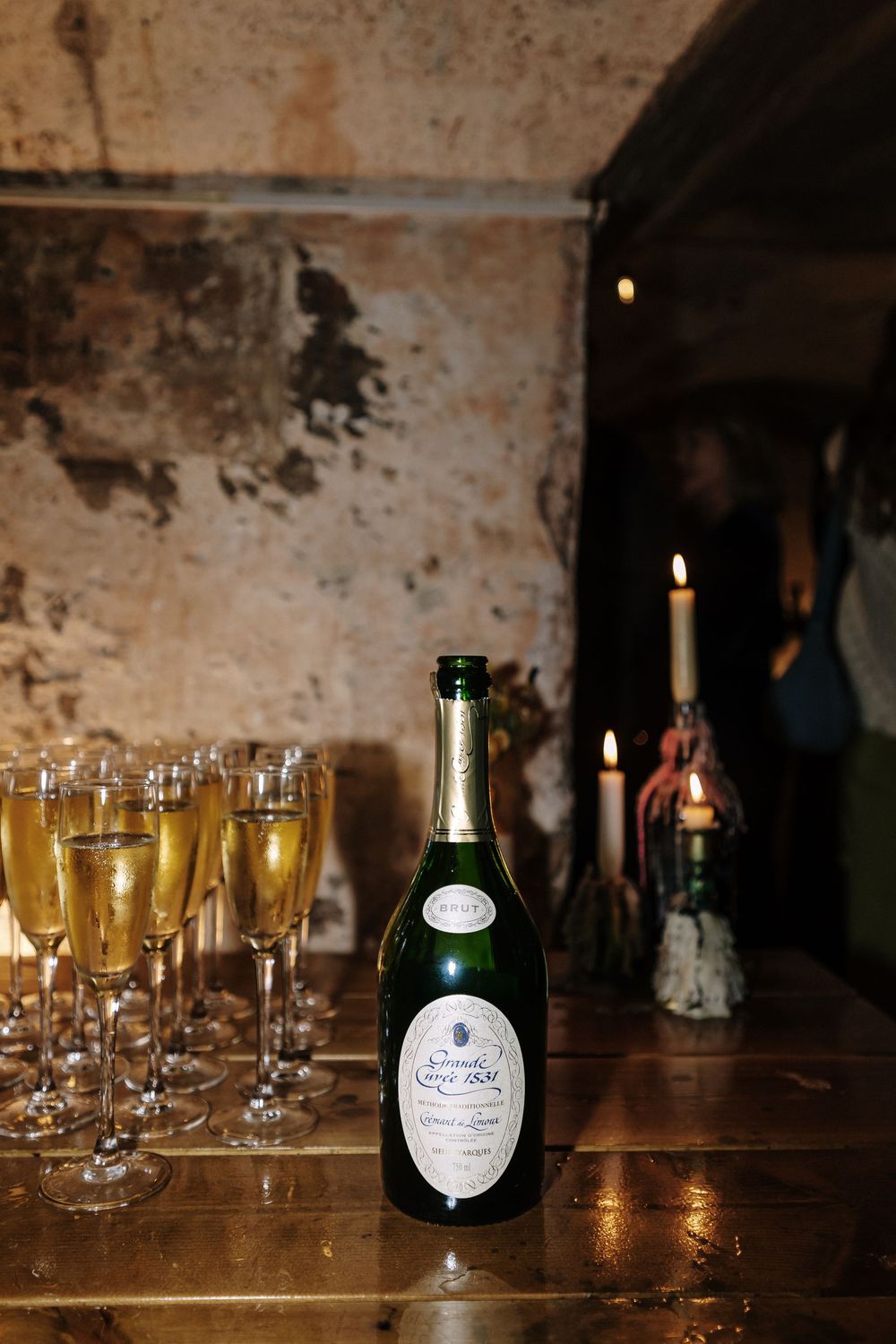 Champagne bottles and glasses arranged on a rustic wooden table with candlelight.