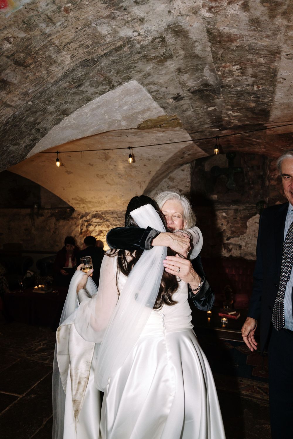 Wedding guests dancing in a rustic stone cellar venue with atmospheric lighting.