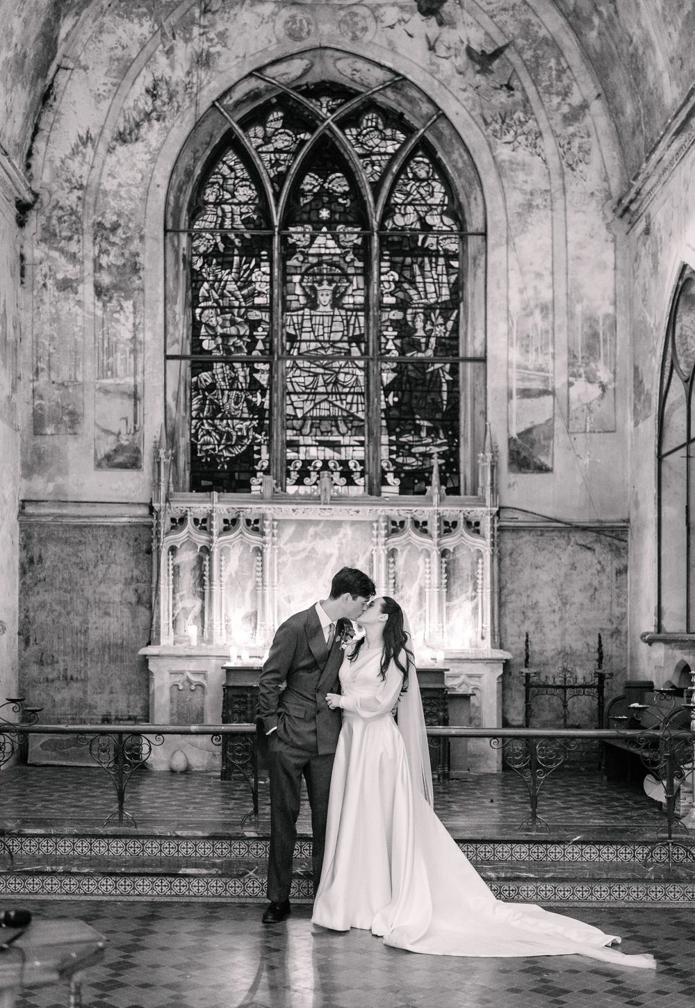 Black and white wedding photos showing a couple in a historic church with stained glass windows and stone walls.
