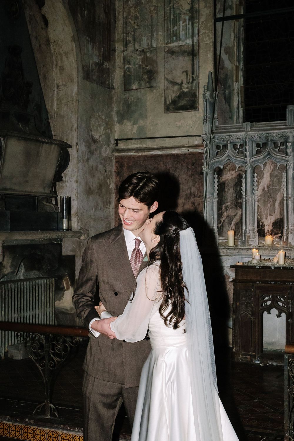 A romantic wedding moment in a historic venue with stone walls and gothic architecture.