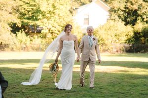 Wedding party walks through a sunlit garden setting during golden hour celebration.