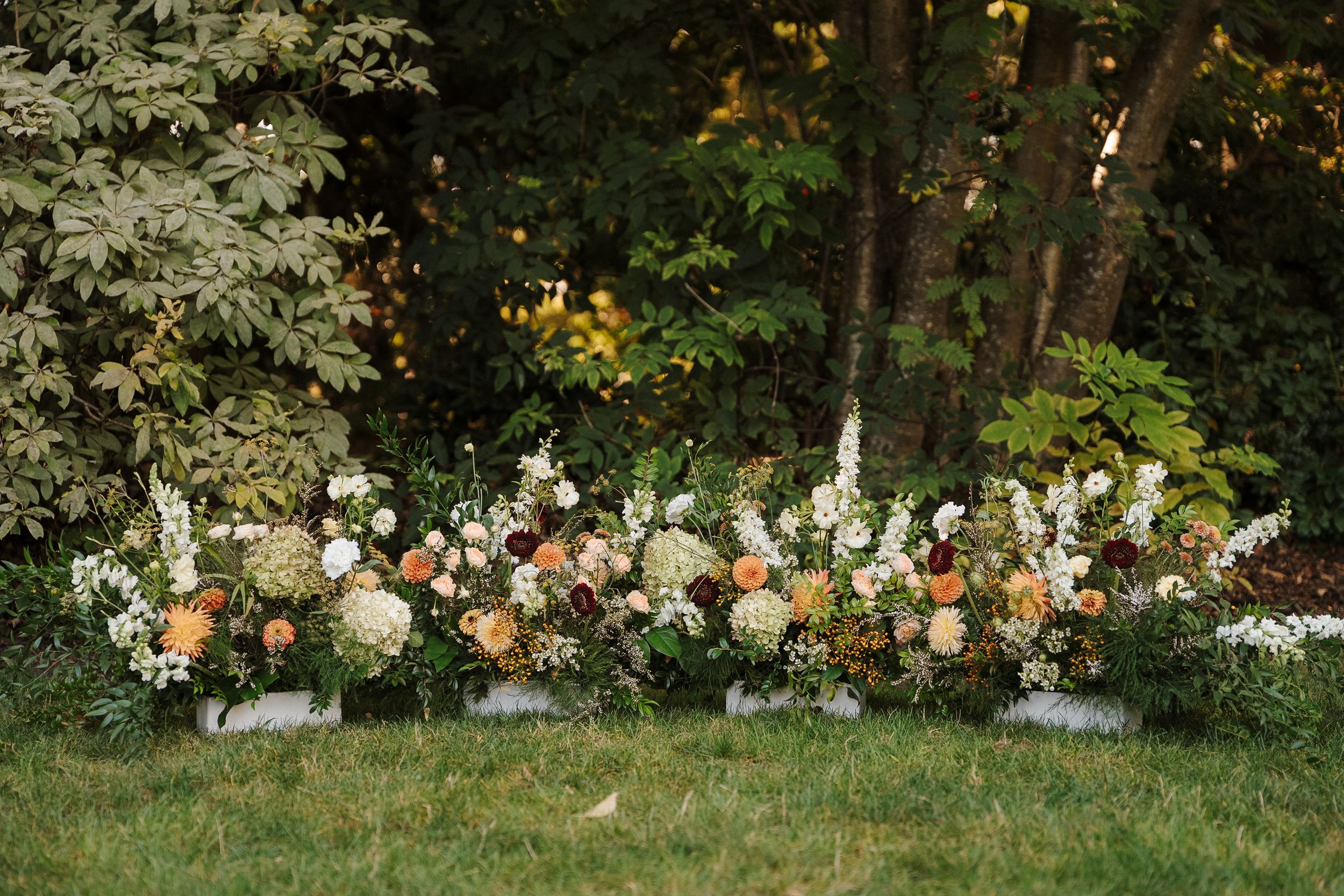 Lush floral arrangement with orange and white blooms decorates an outdoor garden setting at golden hour.