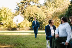 A joyful moment at an outdoor wedding venue with guests gathered on a sunny lawn.