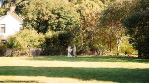 Scenic outdoor wedding venue with lush green grass and trees creating a natural backdrop.