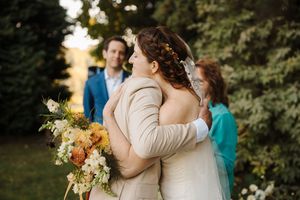 Outdoor wedding ceremony in a lush garden setting with natural golden light filtering through trees.