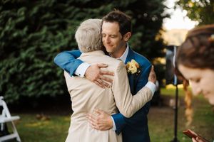 Guests celebrating and embracing during an outdoor wedding reception with greenery in the background.