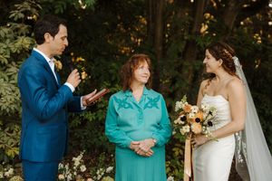 Wedding party shares joyful moments and laughter during outdoor photo session in a wooded setting.