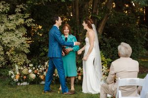 Wedding ceremony in a lush garden setting with golden sunlight filtering through trees and floral decorations.