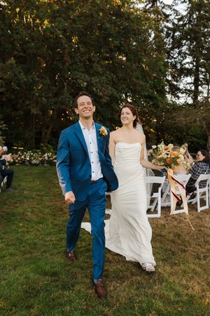 Couple in wedding attire playfully swings together on a rustic wooden swing set during golden hour.