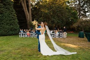 A romantic outdoor wedding ceremony in a garden setting with white chairs and flowing veils catching the golden light.
