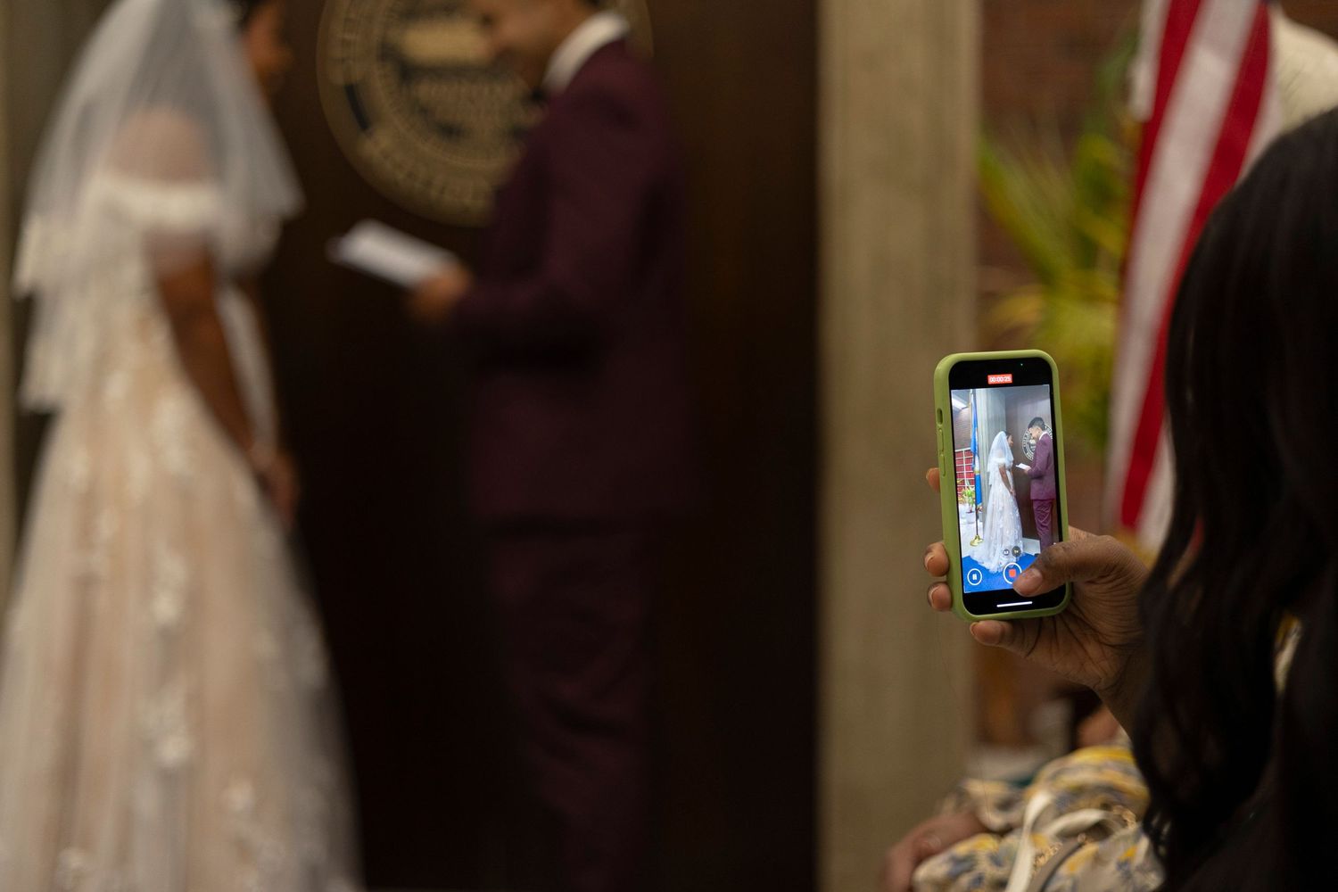 A wedding ceremony in progress with the bride and groom standing at an altar decorated with American flags.