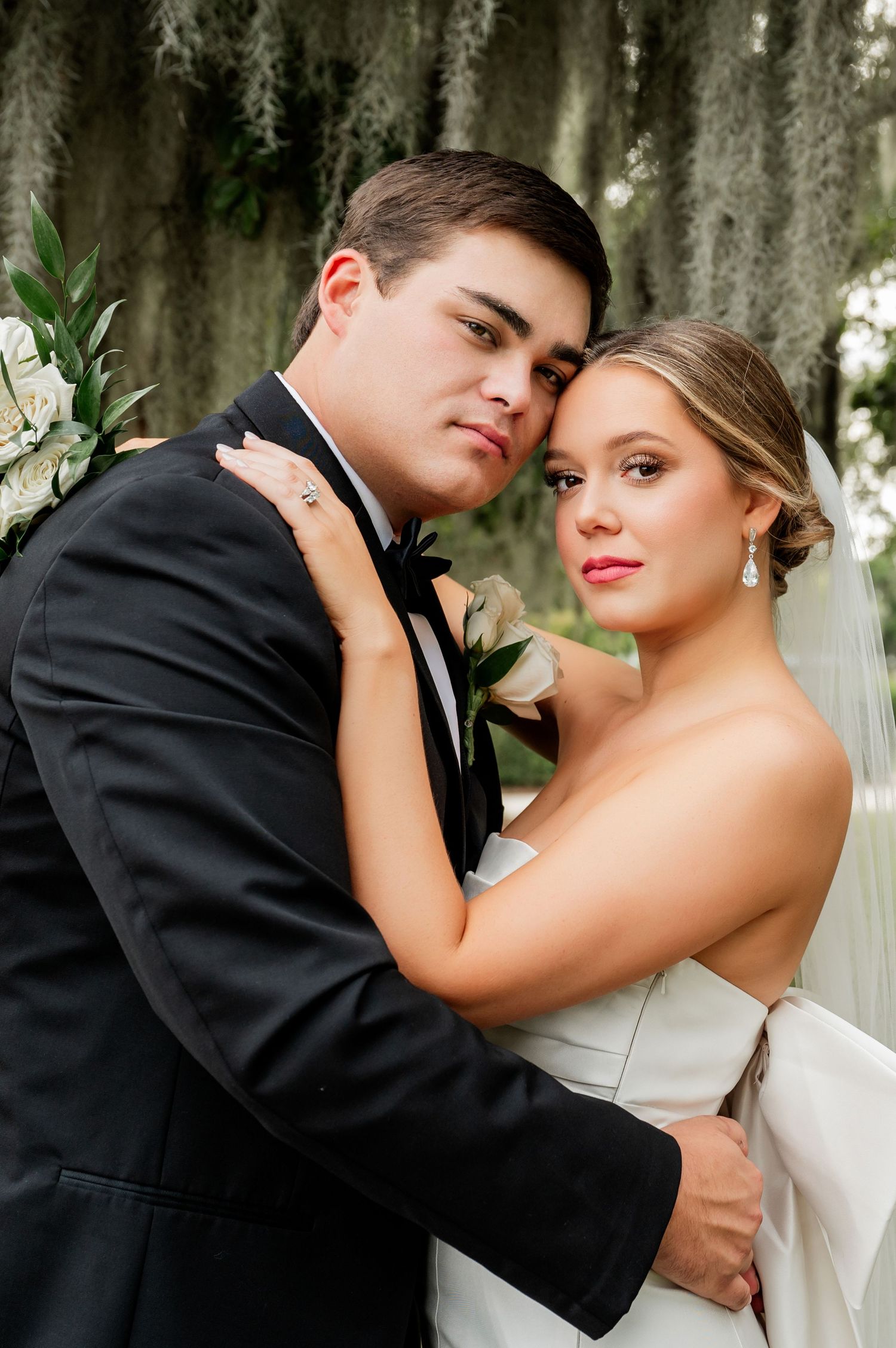 Romantic wedding portraits with Spanish moss and white flowers in the background.