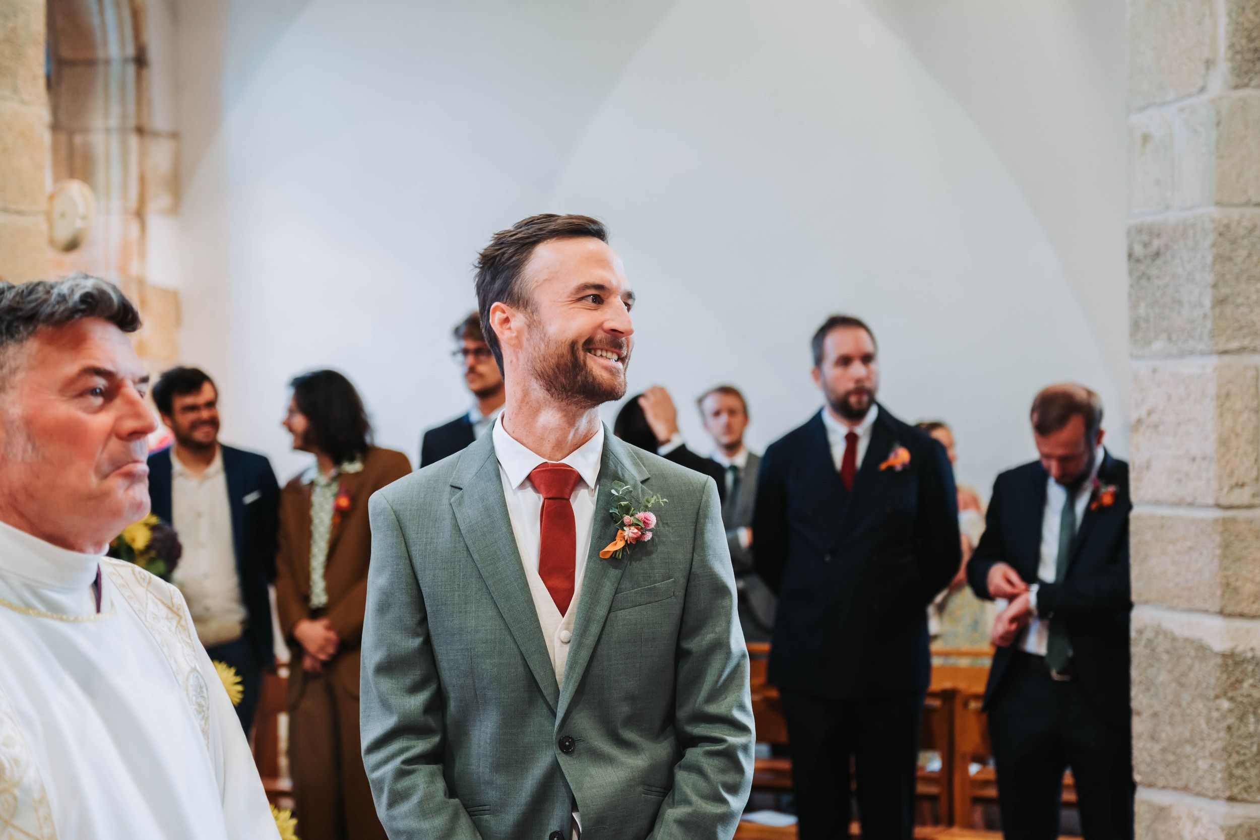 Marié souriant pendant la cérémonie de mariage dans une église en pierre en Bretagne.