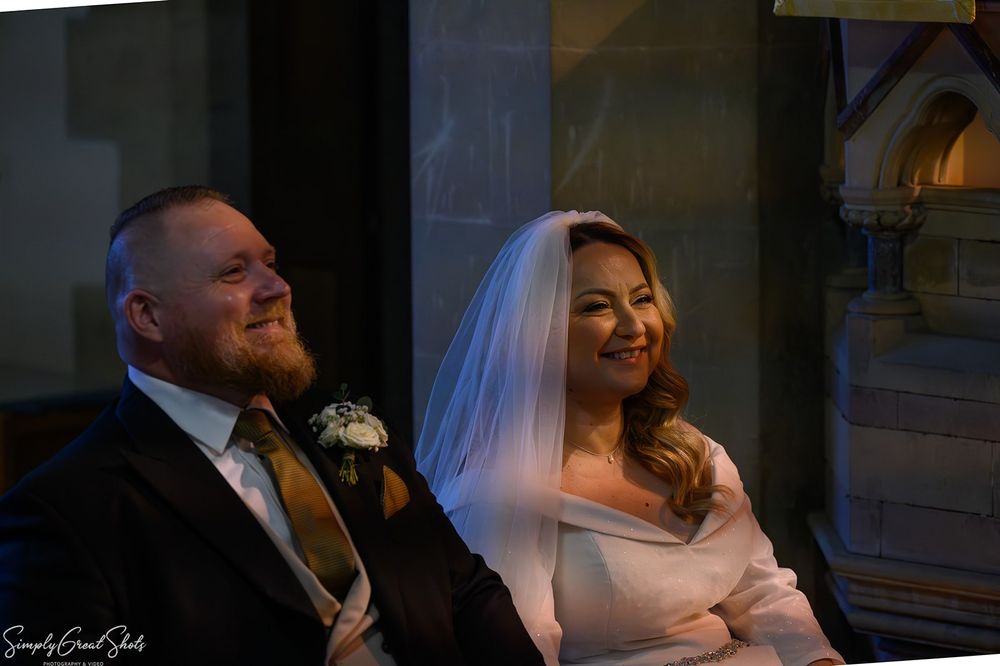 Bride Maria and groom Richard seated during wedding ceremony at St Andrews C of E Church Oxfordshire