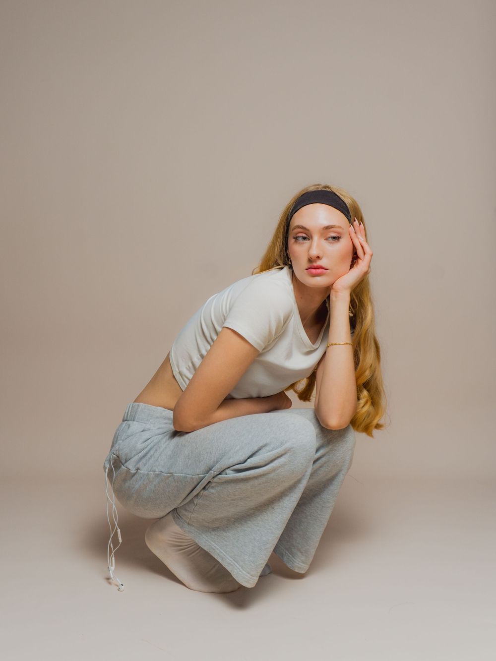 Model in casual grey loungewear strikes dynamic poses on studio floor with neutral backdrop.