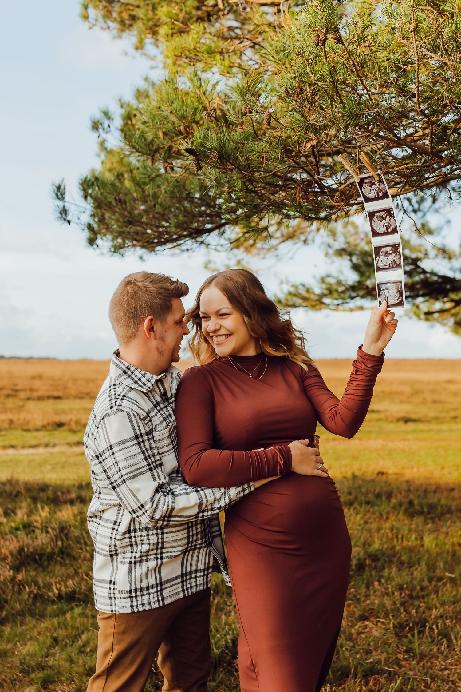 A maternity couple posing together in the New Forest, smiling and holding each other.