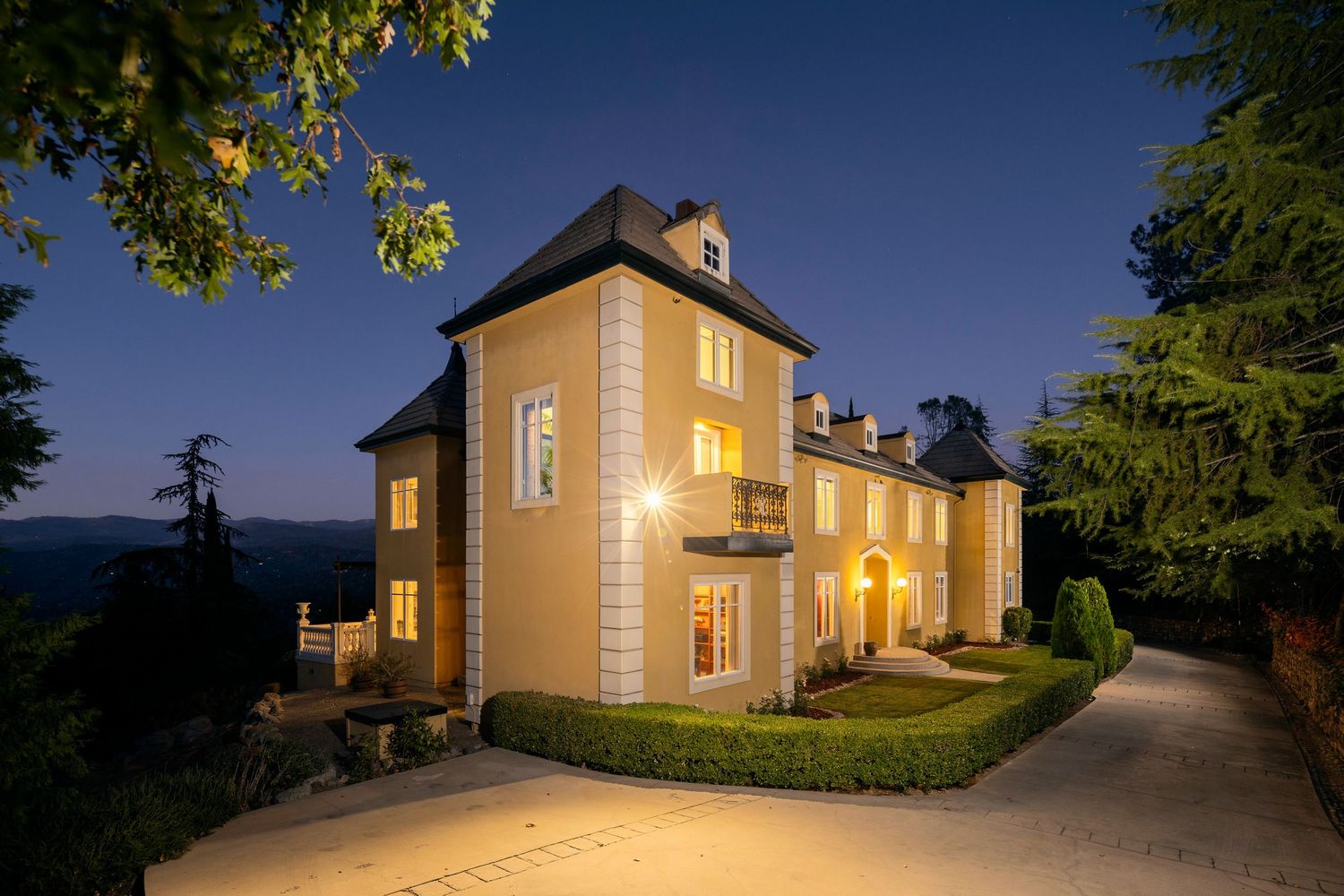 A yellow house with illuminated windows glows warmly against a twilight sky as seen from multiple exterior angles.