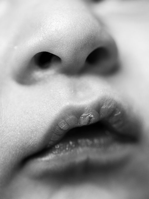 A black and white artistic close-up photograph of lips in a soft, dreamy style with blurred edges.