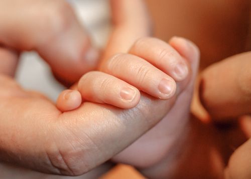 Close-up macro shots of tiny baby fingers and hands in warm lighting.