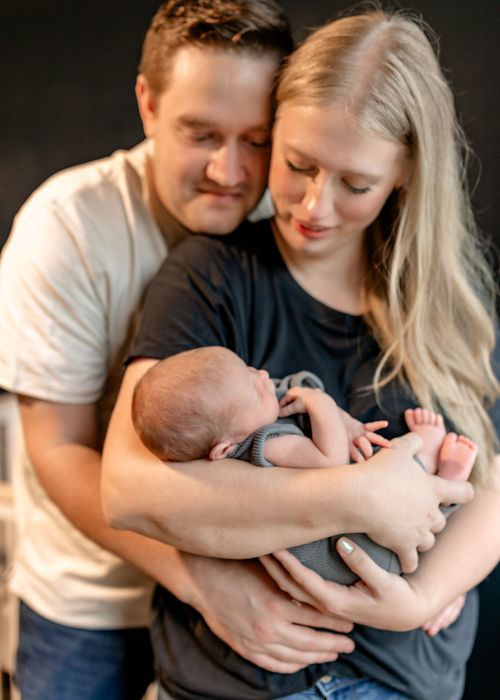 A couple holds and gazes lovingly at their newborn baby in a series of intimate black and white photographs.