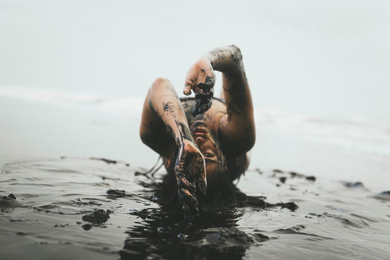 A series of artistic black and white photographs showing hands emerging from dark water in various poses.
