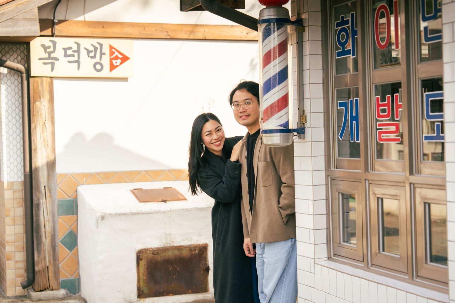 Panoramic view of a Korean barbershop storefront with traditional red and white striped pole and signage.