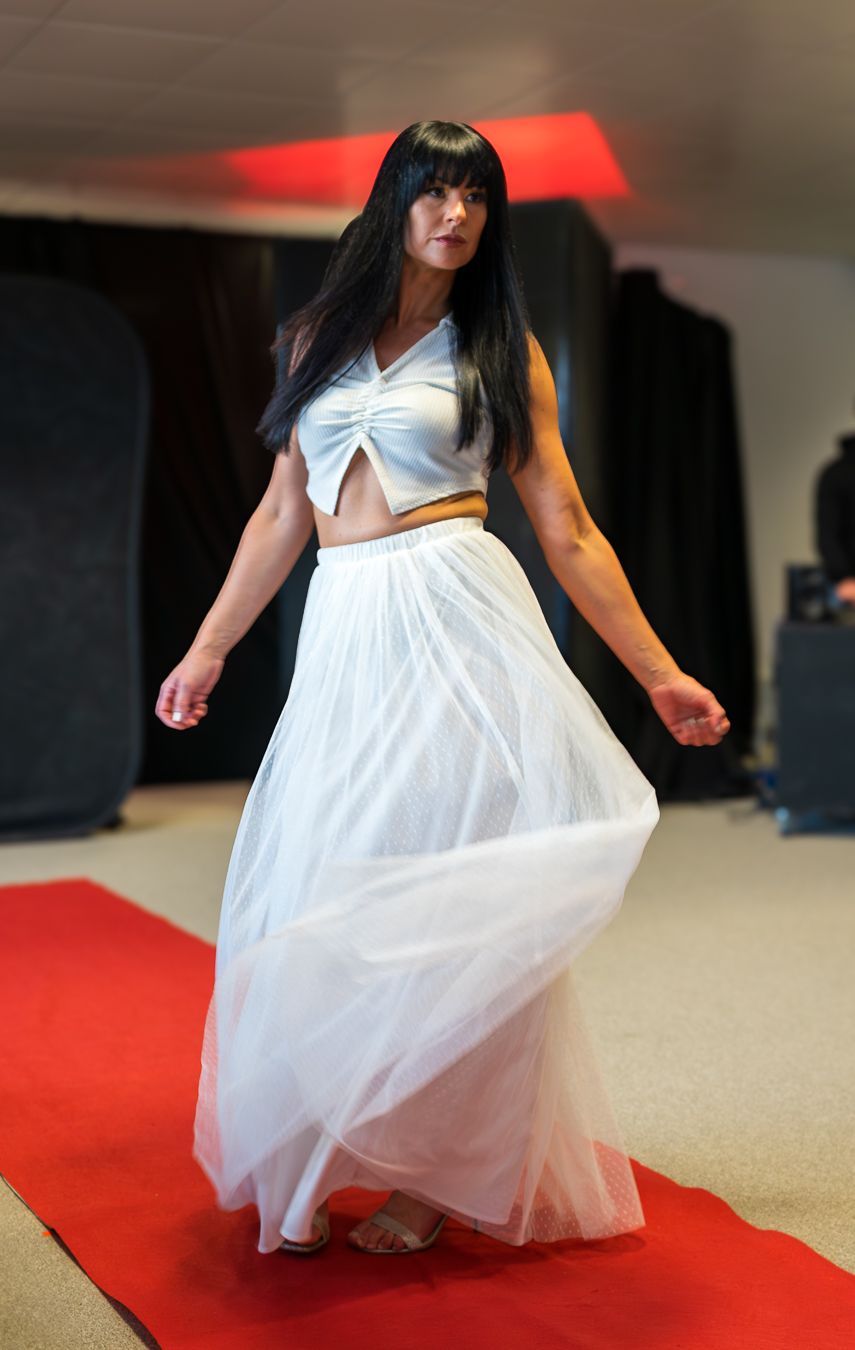 A person in a flowing white dress twirls on a red carpet, creating an elegant spinning motion effect.