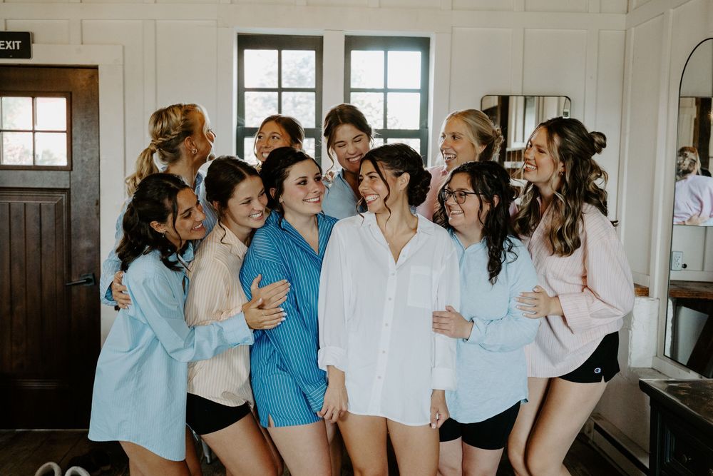 Group of bridesmaids in light blue dresses sharing a joyful moment indoors.
