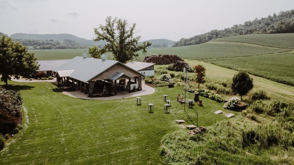 Sweeping panoramic view of farm buildings and barns set against green rolling hills.