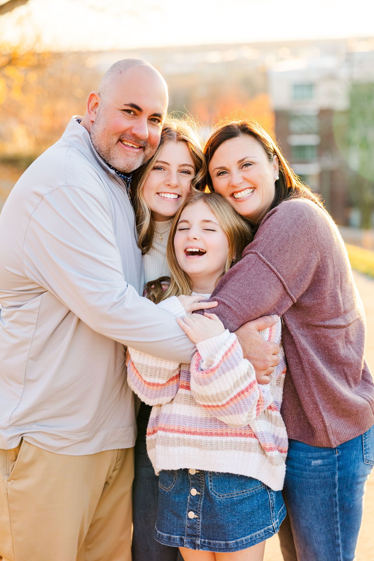 A family shares a joyful embrace while posing together outdoors during golden hour sunset at Libby Hill Park in Richmond, VA.