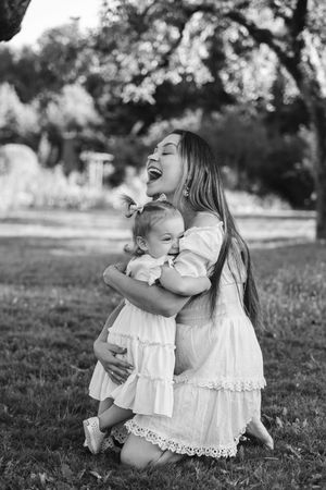 A joyful moment captured in black and white as parent and child share laughter together outdoors in summer.