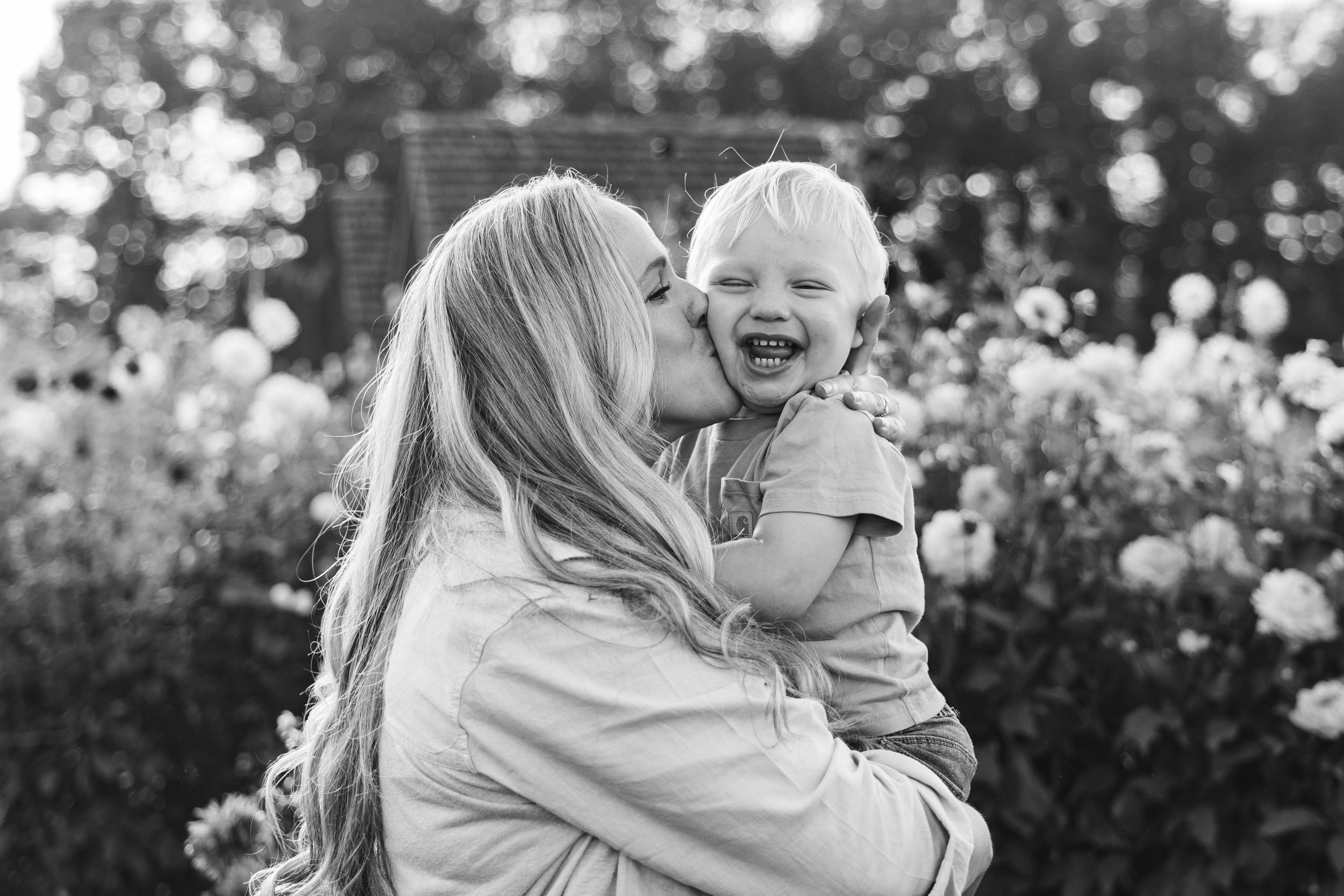 A black and white photo series showing joyful moments between two people in a garden setting.