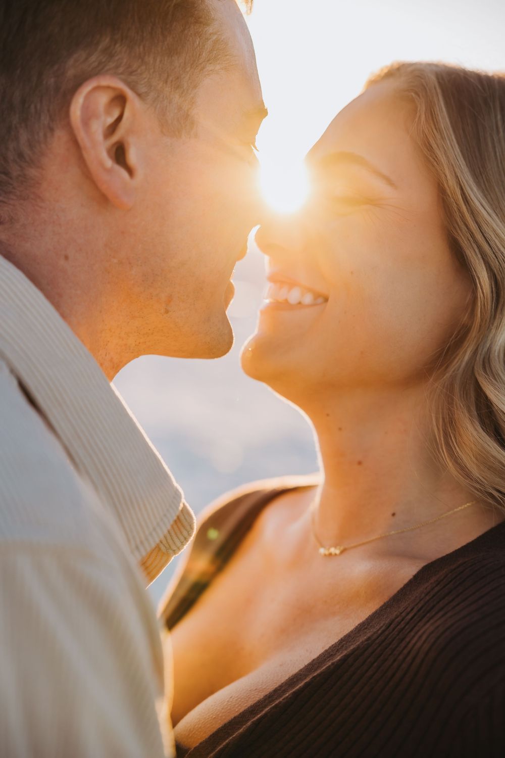 A romantic couple in silhouette share an intimate moment against a warm sunset background.