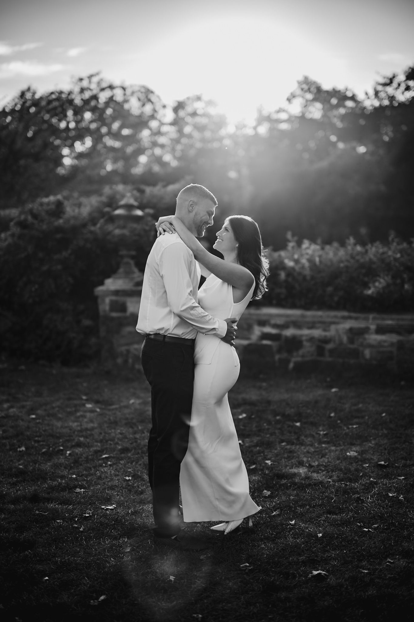 Black and white portrait of couple dancing in romantic outdoor setting at dusk.