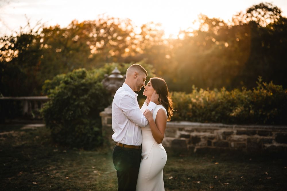 Romantic couple embraces during golden hour sunset in an outdoor garden setting.