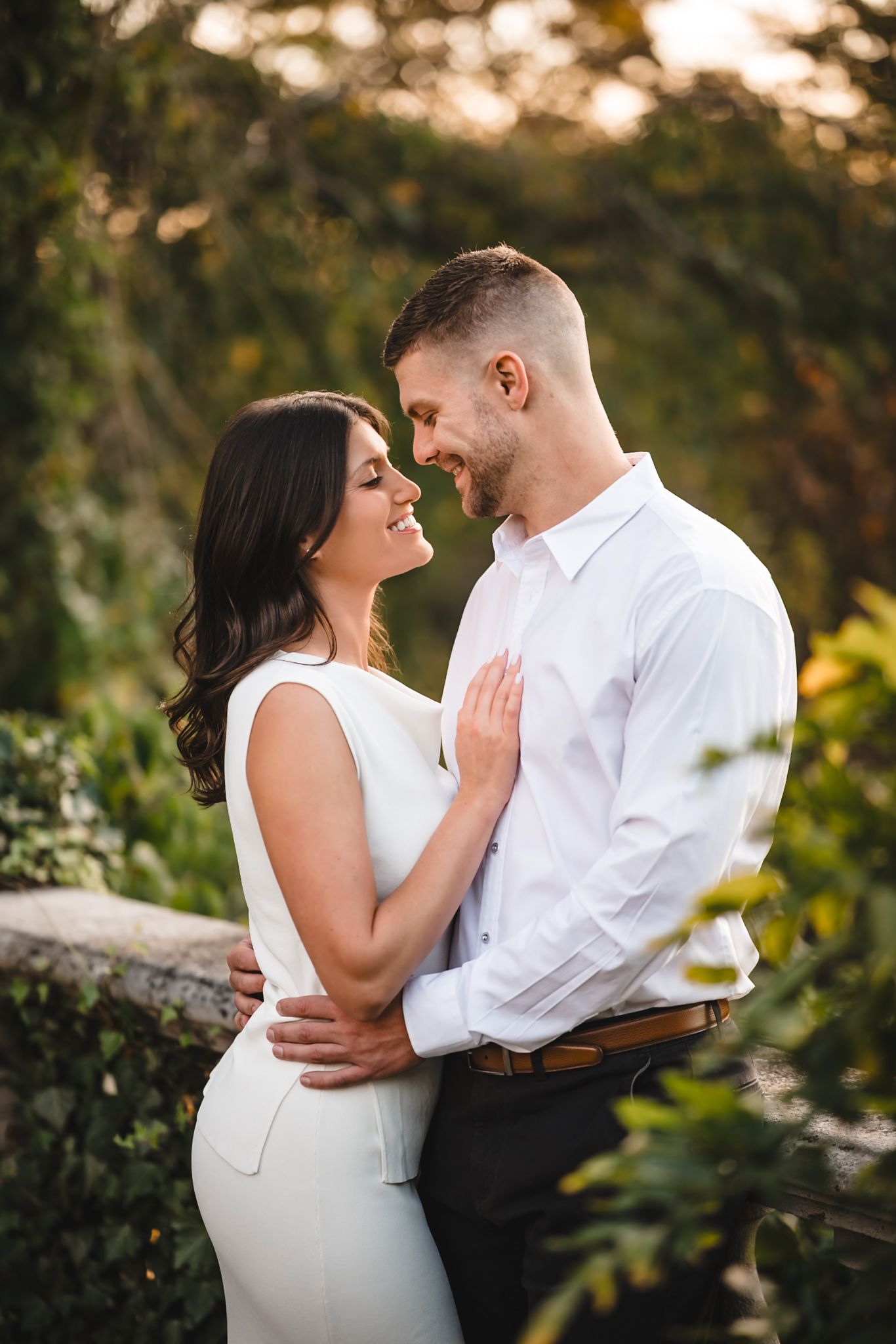 Intimate couple in white and black attire share tender moments during sunset photoshoot.