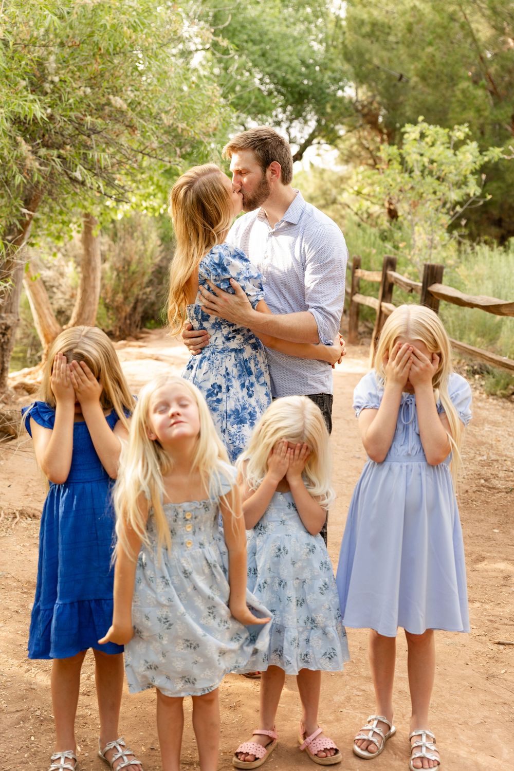 Tonaquint nature center family photos St. George utah mom and dad kissing while 4 young girls close their eyes in the foreground