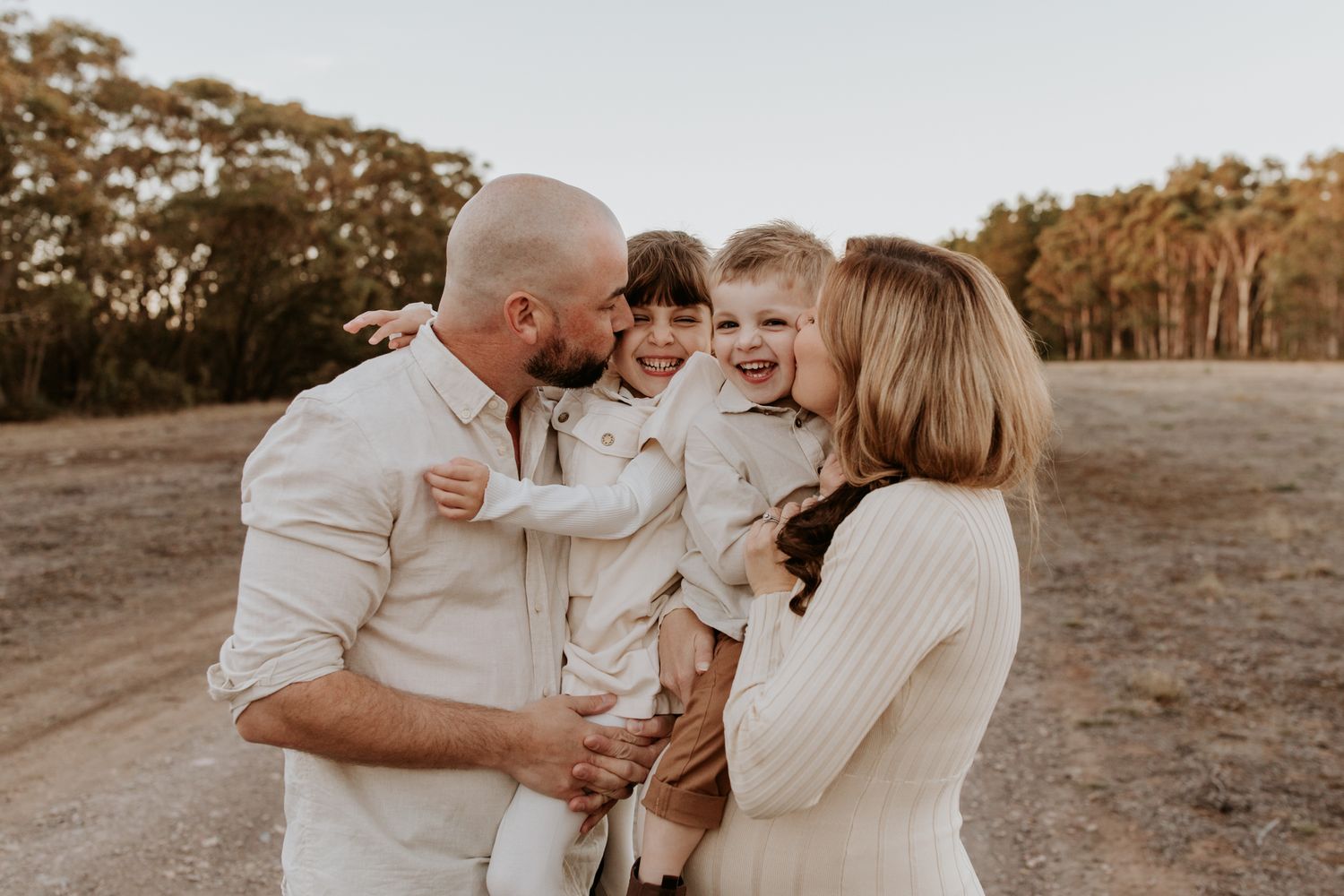 Expecting family of four enjoying cuddles and laughter in Kuitpo Forest, South Australia at golden hour.