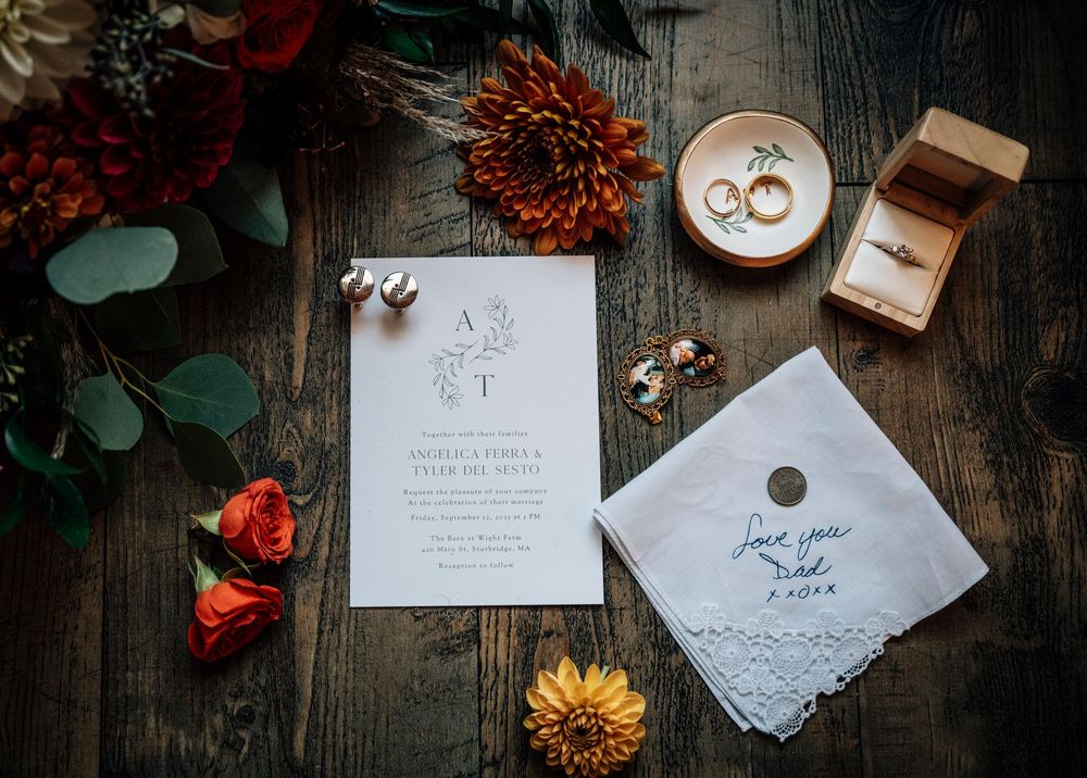 A series of rustic wedding invitations laid out with small orange and red flowers on dark wooden surfaces.